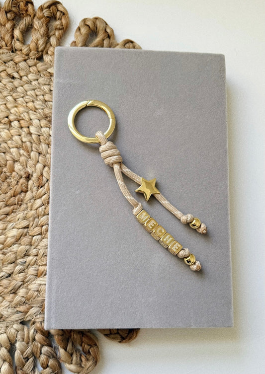 Keychain with star and text on a gray surface, with woven mat in the background